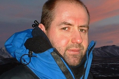 Eine Nahaufnahme von unserem contrastravel Reiseberater, wie er in seiner dicken blau-schwarzen Jacke seitlich in die Kamera schaut.