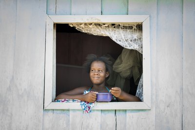 Eine Einheimische blickt auf Sao Tomé zufrieden aus einem Fenster