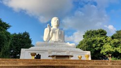 Am Kopf einer Treppe steht eine große weiße Buddha-Skulptur.