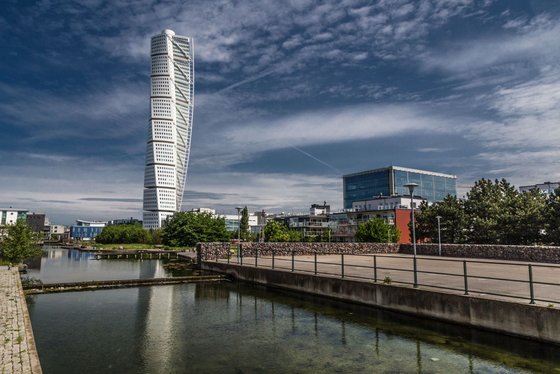 Am vorderen Bildrand entlang zieht sich ein Kanal, dahinter erhebt sich das gedrehte Hochhaus Turning Torso in Malmö.
