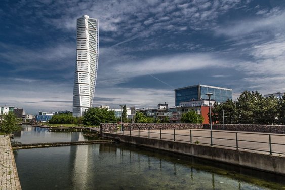 Der Turning Torso des Architekten Calatrava in Malmö Am vorderen Bildrand entlang zieht sich ein Kanal, dahinter erhebt sich das gedrehte Hochhaus Turning Torso in Malmö.