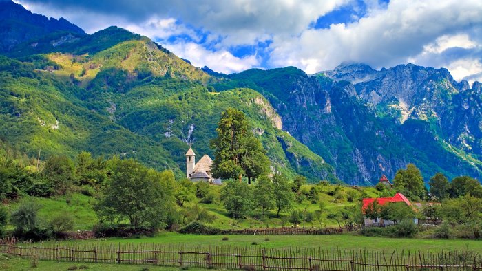 Blick auf ein einsames Dorf vor der Berglandschaft der Albanischen Alpen