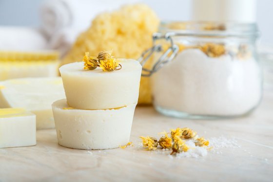 Umweltfreundliches Duschgel Anordnung von Duschgelbars, Kamillenblüten und Duschschwamm