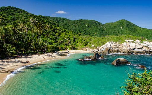 flache Badebucht am Strand, umgeben von Palmen und Bergen