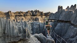 Zwei Wanderer überqueren eine Brücke im Kalksteinfelsengebirge auf Madagaskar