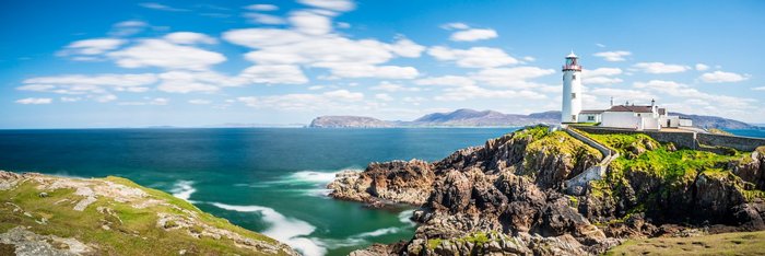 Leuchtturm auf einer Klippe in Irland, umgeben von dem Atlantischen Ozean und steilen Felswänden.