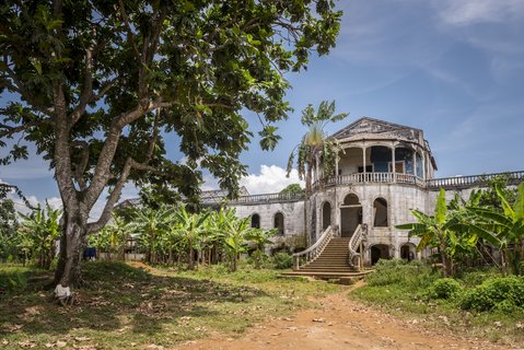 Der Treppenaufgang eines leerstehenden Hospitals aus der Kolonialzeit mit Palmen und einem Baum im Vordergrund