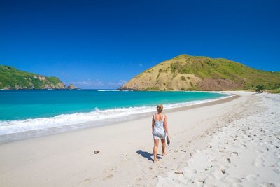 Eine Frau läuft einen weißen Strand entlang