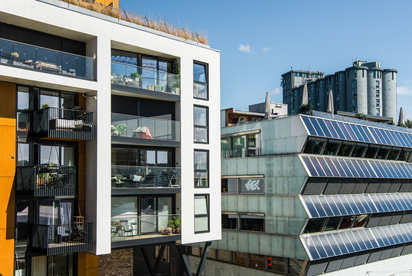 Oslo fördert Solarenergie Man seht nahsichtig zwei mehrgeschossige moderne Gebäude, das rechte ist mit Solarpanelen ausgestattet.