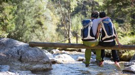 Wandern in Österreich Ein Paar sitzt auf einem Baumstamm und macht eine kurze Wanderpause in Österreich.