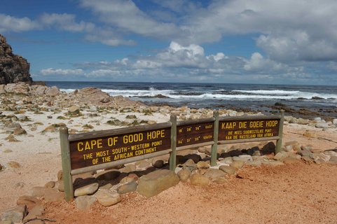 langes Holzschild mit Aufschrift, im Hintergrund das Meer