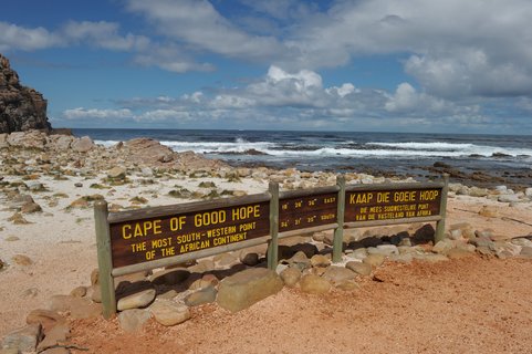 langes Holzschild mit Aufschrift, im Hintergrund das Meer