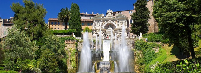 Parkanlage mit Schloss, in dem ein Brunnen Wasserfontänen schießt