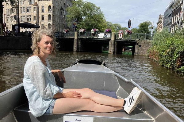 Ein Bild von unserer contrastravel Reiseberaterin Steffie, wie sie auf einem Boot auf dem Fluss sitzt und die Kamera lächelt.