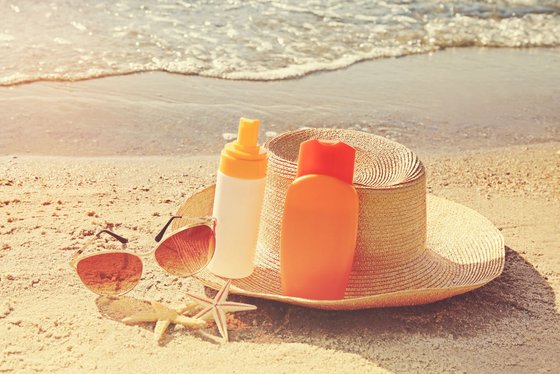 Umweltfreundliche Sonnencremes Sonnencreme, Sonnenhut und Sonnenbrille liegen am Strand