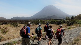 Eine Gruppe von Reisenden wandert auf der Insel Fogo auf den Kapverden, im Hintergrund zu sehen ist der Vulkan Pico..