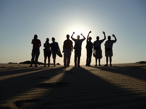 Silhouette einer Reisegruppe in den Dünen bei Sonnenuntergang