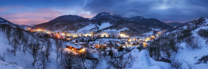 Leuchtende Häuser im Tal bei Nacht im Winter