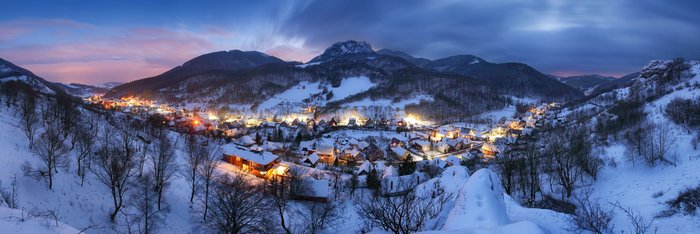 Leuchtende Häuser im Tal bei Nacht im Winter