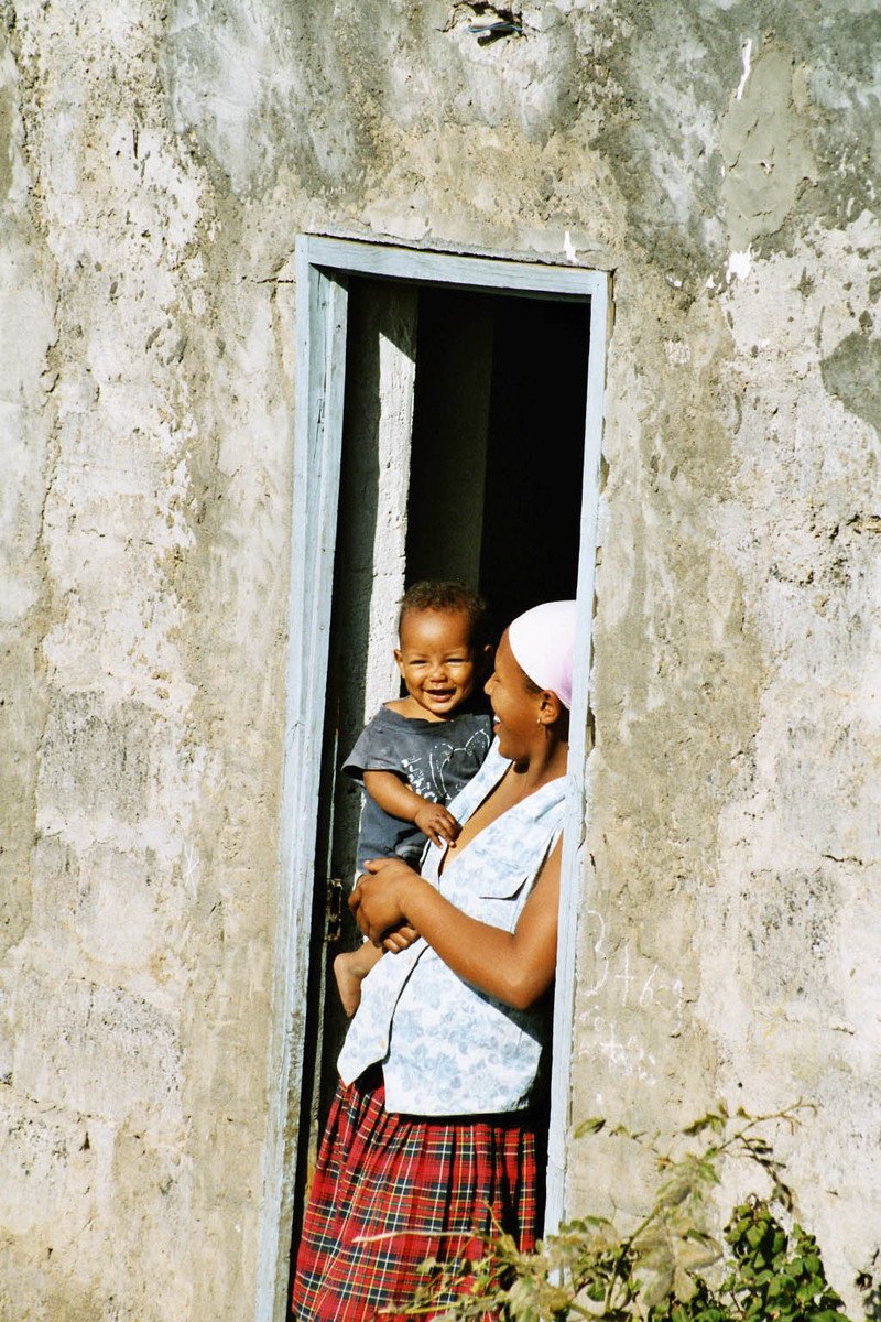 Frau steht mit ihrem Baby auf dem Arm angelehnt an der Tür