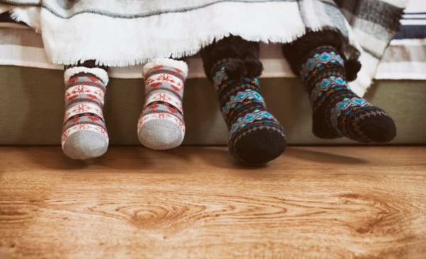 Typisch schwedische Socken Die Abbildung zeigt zwei Sockenpaare typischer schwedischer Socken, die von Kindern getragen werden und unter einer Kuscheldecke hervorgucken.