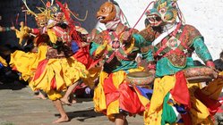 Maskentänzer in Bhutan Männer tanzen einen Maskentanz in bunten Kostümen