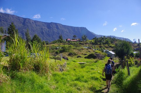 Eine Wandergruppe läuft Richtung eines Dorfes in der Talebene