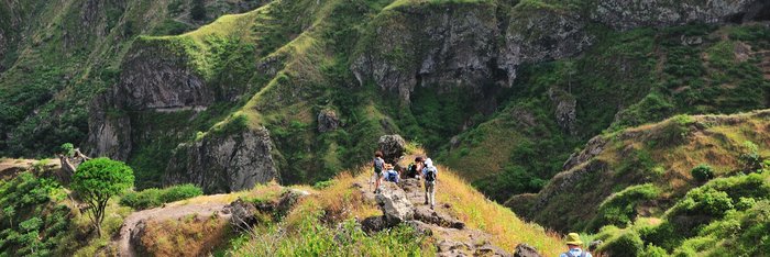 Wanderer auf einem steilen Wanderweg in grüner Landschaft auf Santo Antao.