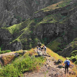 Wanderer auf einem steilen Wanderweg in grüner Landschaft auf Santo Antao.