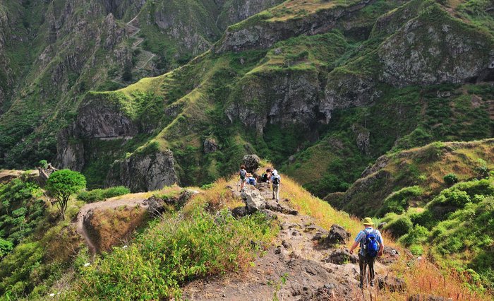 Wanderer auf einem steilen Wanderweg in grüner Landschaft auf Santo Antao.