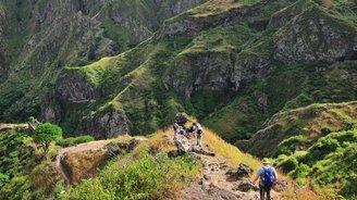 Wanderer auf einem steilen Wanderweg in grüner Landschaft auf Santo Antao.