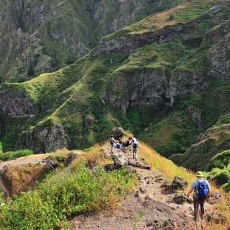 Wanderer auf einem steilen Wanderweg in grüner Landschaft auf Santo Antao.