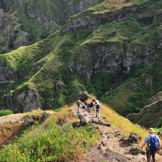 Wanderer auf einem steilen Wanderweg in grüner Landschaft auf Santo Antao.