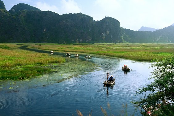 Mehrere Boote fahren auf einem Fluss im Nationalpark in Vietnam.