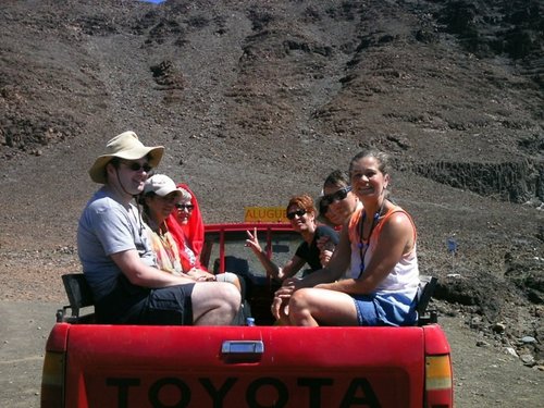 Reisegruppe sitzt in einem offenen, roten Auto 