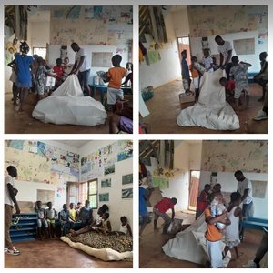 Eine Anordnung von vier Fotos im Quadrat, auf denen ein großer weißer Müllsack umringt von afrikanischen Kindern in einem Innenraum zu sehen ist.