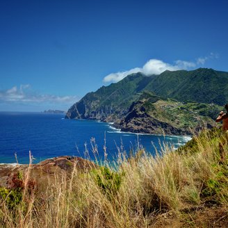 Zwei Frauen blicken von einem Hügel aus auf das Meer