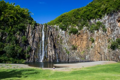 Ein schmaler Wasserfall stürzt von einer hohen Bergwand hinunter 