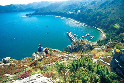 Wanderer blicken bei schönstem Sonnenschein in die malerische Bucht von St. John auf Jersey