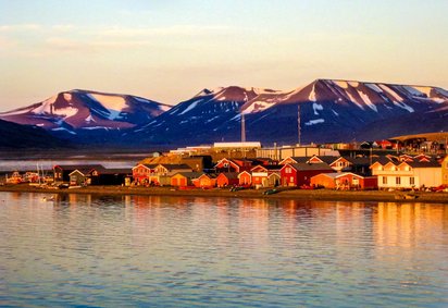Norwegens Norden, wo die Sonne im Sommer nicht untergeht Die Mitternachtssonne bescheint einen norwegischen Küstenort mit ihrem orangenen Licht.