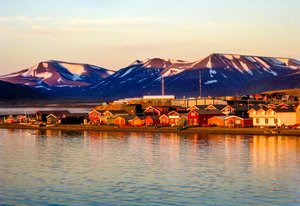 Die Mitternachtssonne bescheint einen norwegischen Küstenort mit ihrem orangenen Licht.