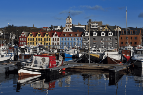 Vom Hafen aus, in dem kleine Boote ankern, blickt man auf die bunten Häuser von Torshavn.
