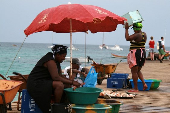 Eine einheimische Frau säubert Fische auf einem Steg über dem Meer auf Sal