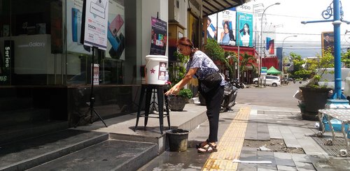 Eine Frau wäscht ihre Handy vor einem Geschäft in Indonesien.