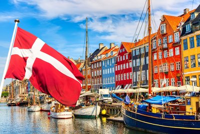 Vor den bunten Häusern am Nyhavn in Kopenhagen weht die dänische Flagge.