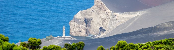 Ausblick auf das Meer und die Küste, an der ein Leuchtturm steht.