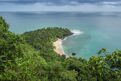 Banana Beach von Príncipe auf São Tomé und Príncipe Dicht bewaldeter Küstenabschnitt mit Blick auf einen einsamen Strand und Wolken am Horizont