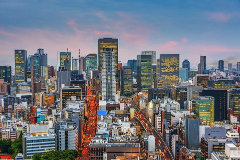 Die Skyline der Stadt Osaka in der Dämmerung mit vielbefahrenen Straßen und Wolkenkratzern.