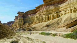 Wanderer vor einer Felswand in der Namib Wüste in Angola.