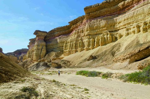 Wanderer vor einer Felswand in der Namib Wüste in Angola.